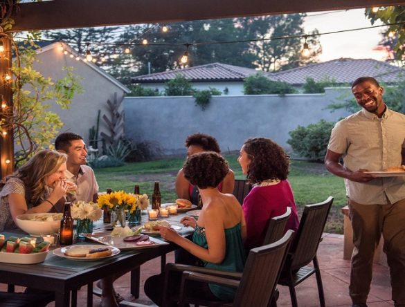 Group of friends enjoying backyard barbecue at table in backyard
